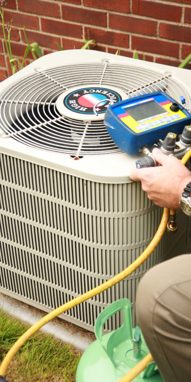 FREEDOM HVAC technician testing refrigerant levels and system efficiency on an outdoor air conditioning unit in Joplin, MO.