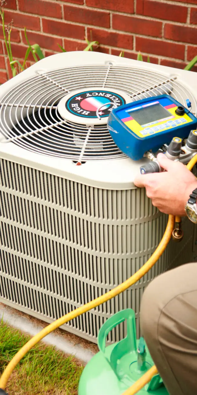FREEDOM HVAC technician testing refrigerant levels and system efficiency on an outdoor air conditioning unit in Joplin, MO.